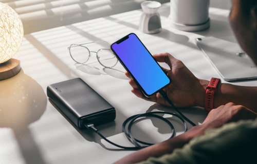Man holding an iPhone 12 mockup plugged into a power bank