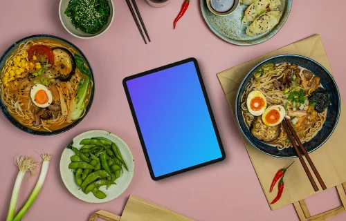 Tablet mockup between ramen bowls
