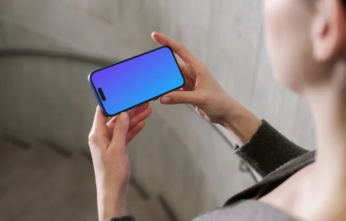 iPhone 16 mockup in a hand against concrete backdrop