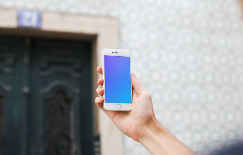 Man holding iPhone 7 mockup in front of the wall