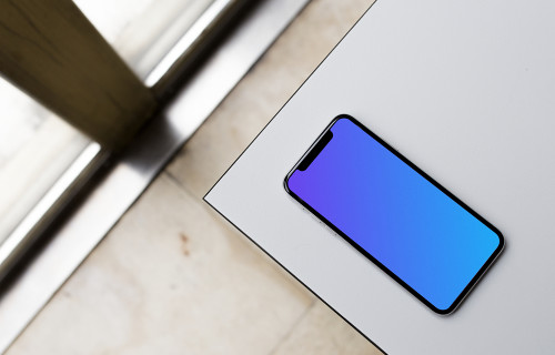 Top view mockup of iPhone X on the gray table