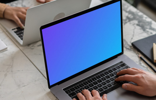 Notebook mockup on a table opposite another MacBook Pro