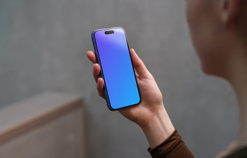 iPhone 16 mockup in a woman's hand with concrete backdrop